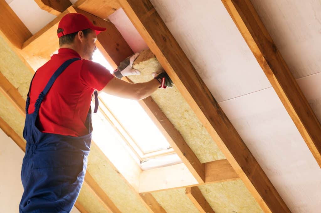 house attic insulation - construction worker installing rock woo