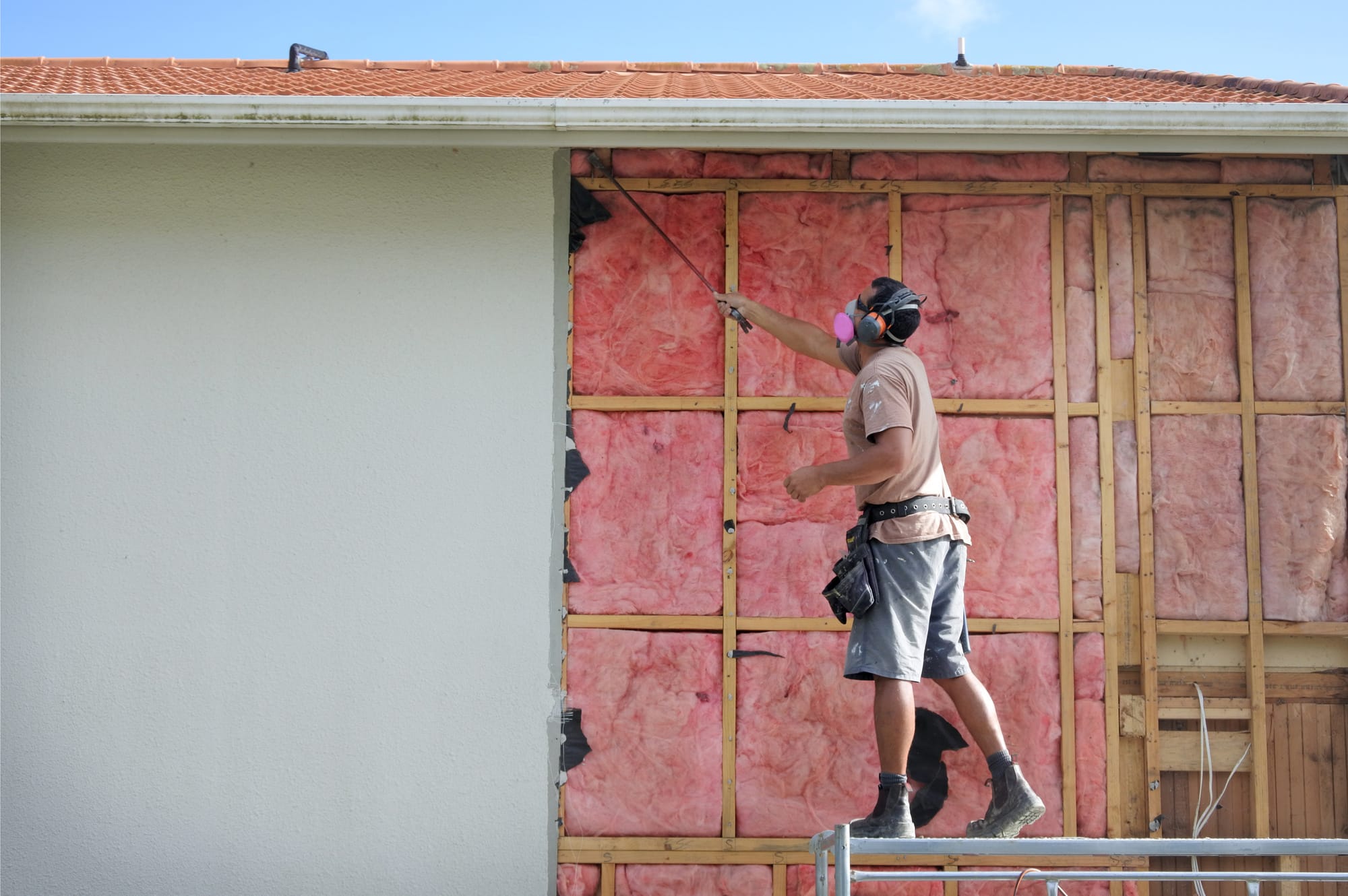 Builder removing an old fiberglass wall insulation from a building