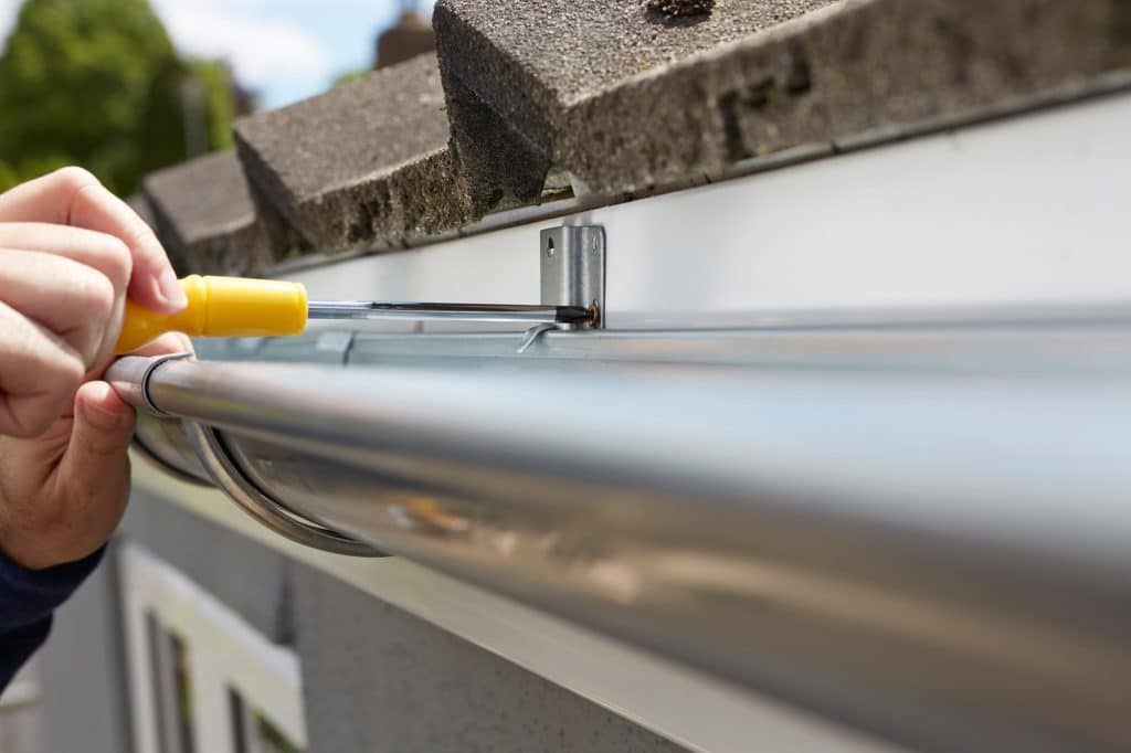 Close Up Of Man Replacing Guttering On Exterior Of House