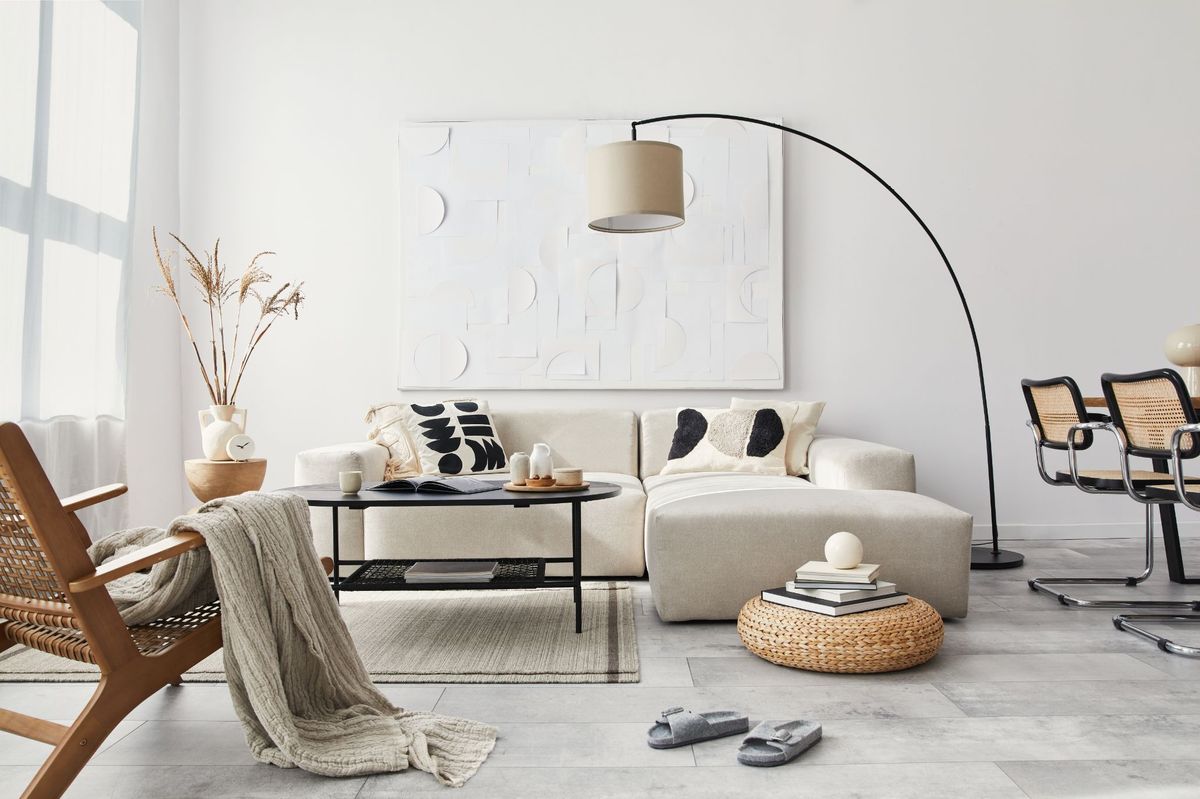 A white living room with a rug, chair, and table. The room is well-lit with an LED floor lamp