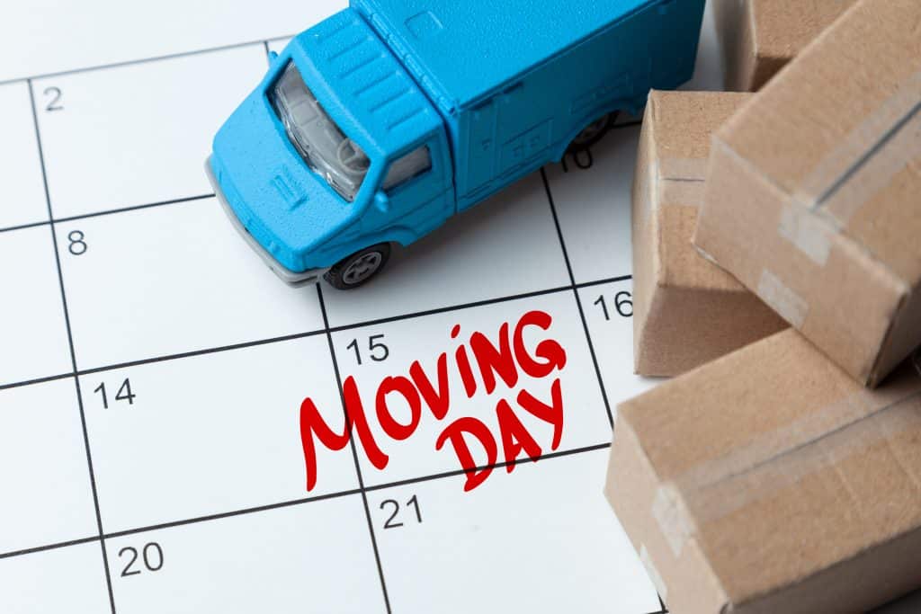 Moving day on the calendar is written in red. Calendar with a note with cardboard boxes and truck